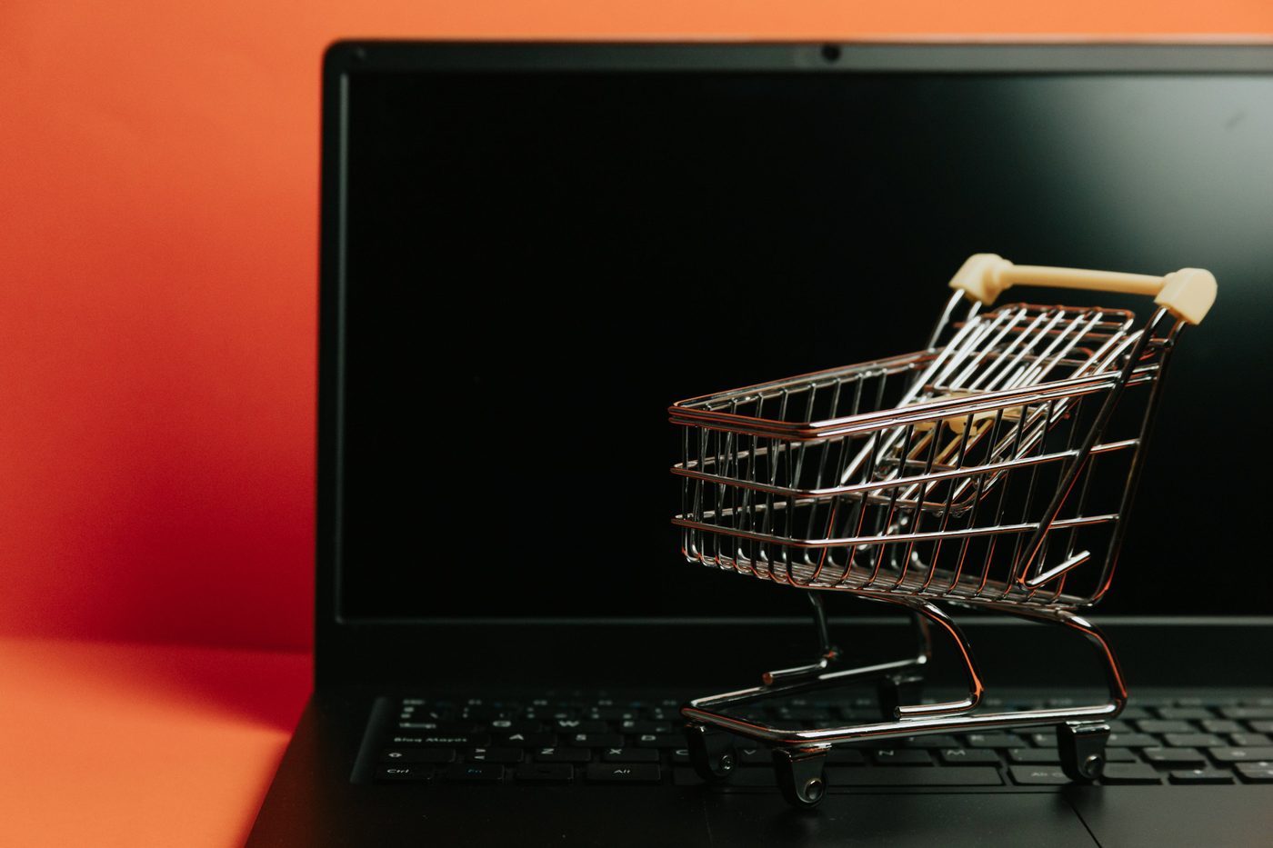 Miniatur-Einkaufswagen auf einem Laptop als Symbolbild für E-Commerce und Online-Shop-Support